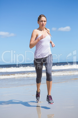 Focused fit blonde jogging on the beach