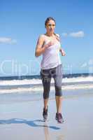 Focused fit blonde jogging on the beach