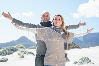 Carefree couple standing on the beach in warm clothing