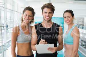 Fit women with trainer taking notes and smiling at camera