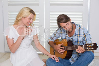 Handsome man serenading his girlfriend with guitar