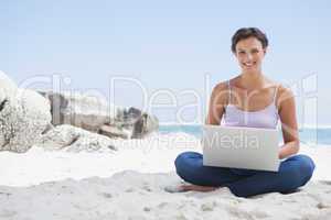 Pretty brunette using laptop on the beach