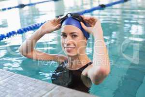 Fit swimmer in the pool smiling at camera