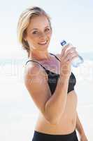 Fit blonde drinking water on the beach