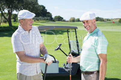 Golfing friends chatting beside their buggy