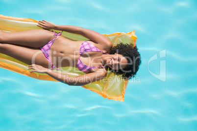 Happy woman lying on lilo in swimming pool