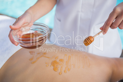 Woman getting a honey beauty treatment poolside