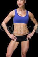 Strong woman posing in sports bra and shorts with hands on hips