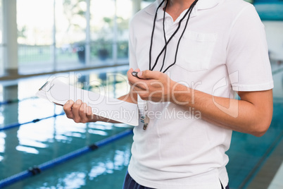 Swimming coach looking at his stopwatch by the pool