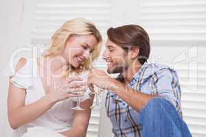Young couple sitting on floor drinking wine