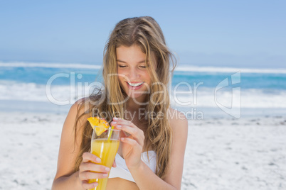 Pretty blonde in white bikini holding cocktail on the beach