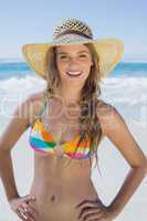 Beautiful girl on the beach smiling in white straw hat and bikin