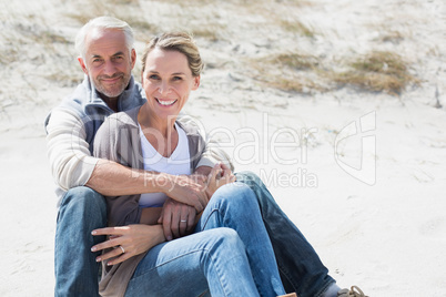 Attractive couple smiling at each other on the beach