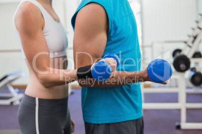 Fit couple exercising with blue dumbbells