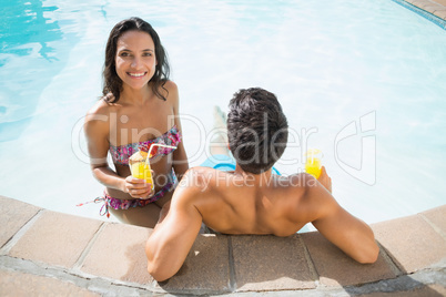 Attractive couple drinking cocktails in the pool