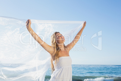 Beautiful calm blonde in white sundress on the beach with scarf