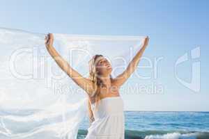 Beautiful calm blonde in white sundress on the beach with scarf