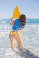 Fit surfer girl standing on the beach with her surfboard