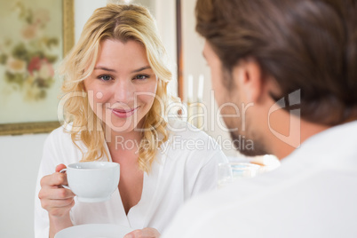 Cute couple in bathrobes having coffee together