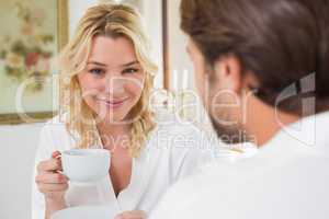 Cute couple in bathrobes having coffee together