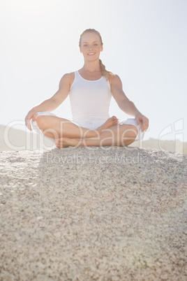 Smiling woman sitting in lotus pose on beach