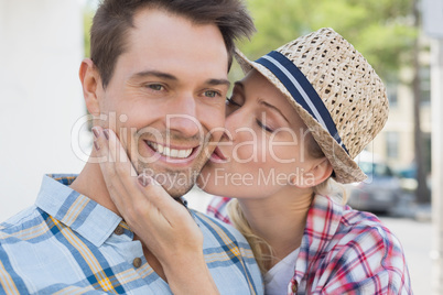 Young hip couple smiling at camera woman kissing mans cheek