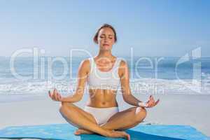 Fit woman sitting in lotus pose on the beach