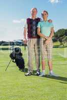 Golfing couple standing smiling at camera