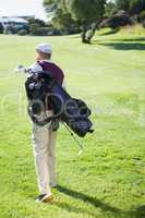 Golf player carrying his bag and walking