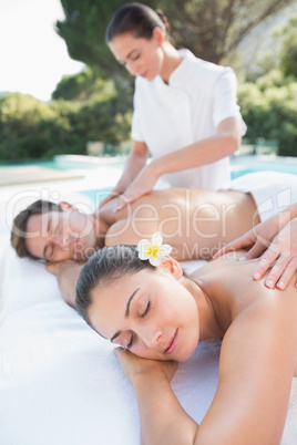 Attractive couple enjoying couples massage poolside