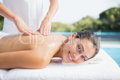 Happy brunette getting a massage poolside