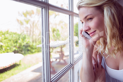 Pretty blonde sitting by the window on a phone call