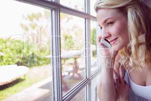 Pretty blonde sitting by the window on a phone call