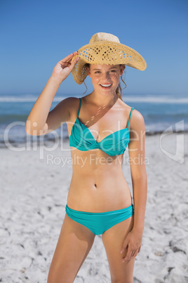 Pretty smiling woman in bikini on beach wearing sunhat