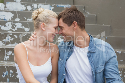 Hip young couple sitting on steps smiling at each other