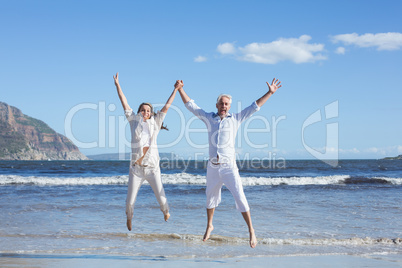 Happy couple jumping up barefoot on the beach