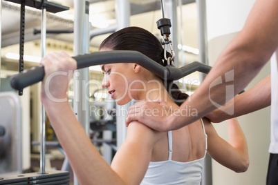 Fit brunette using weights machine for arms with trainer touchin