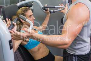 Personal trainer coaching female bodybuilder using weight machin