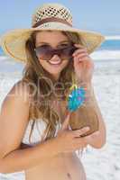 Pretty blonde in white bikini holding coconut drink on the beach