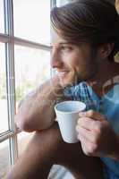 Smiling man sitting by the window having coffee