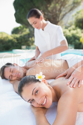 Attractive couple enjoying couples massage poolside