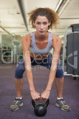 Fit woman squatting with kettlebell
