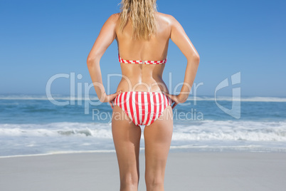 Mid section rear view of fit woman in striped bikini at beach