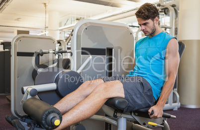 Focused man using weights machine for legs