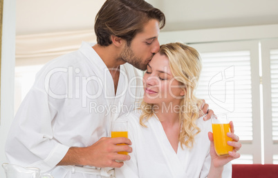 Cute couple in bathrobes drinking orange juice