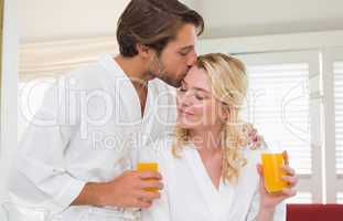 Cute couple in bathrobes drinking orange juice