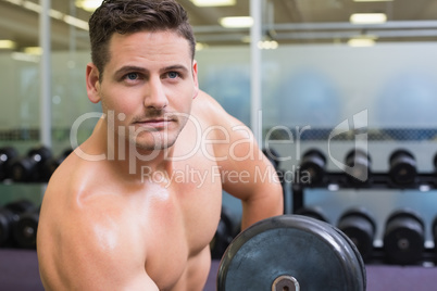 Handsome bodybuilder lifting heavy dumbbell