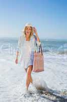 Laughing blonde in sunhat walking in the sea