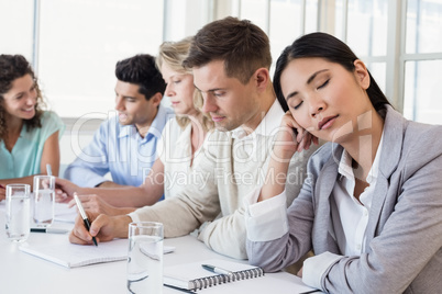 Casual businesswoman falling asleep during meeting