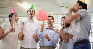 Casual business team celebrating with champagne and party horns